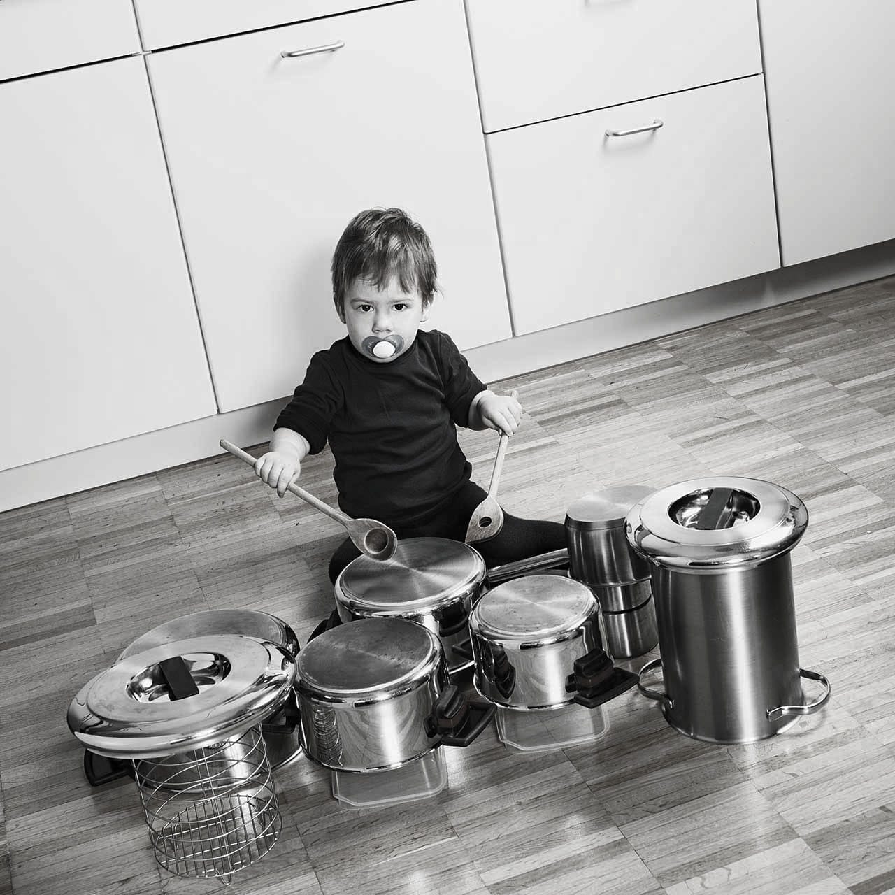 Ein Kleinkind spielt Schlagzeug auf Töpfen.
