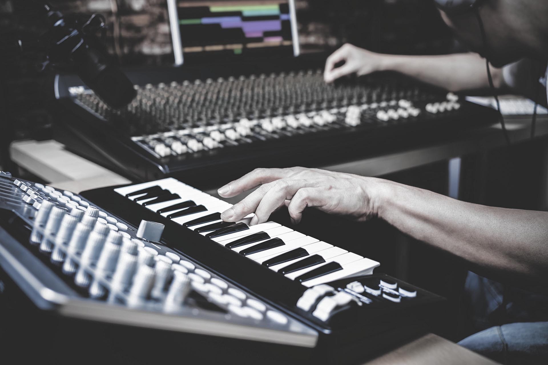 Ein Keyboarder macht auf einem Synthesizer Musik in einem Studio.